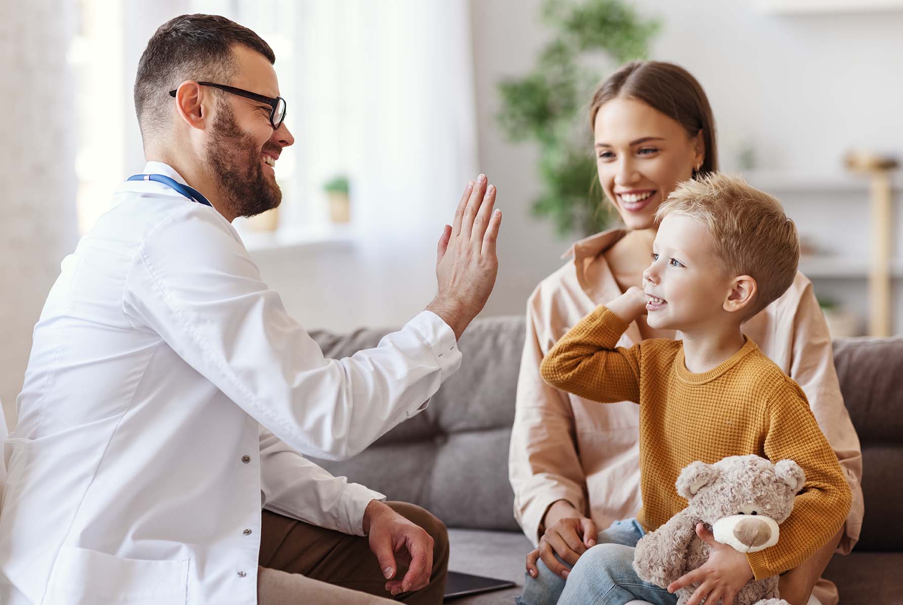 Family doctor pediatrician conducts examination of child boy and giving high five to him.