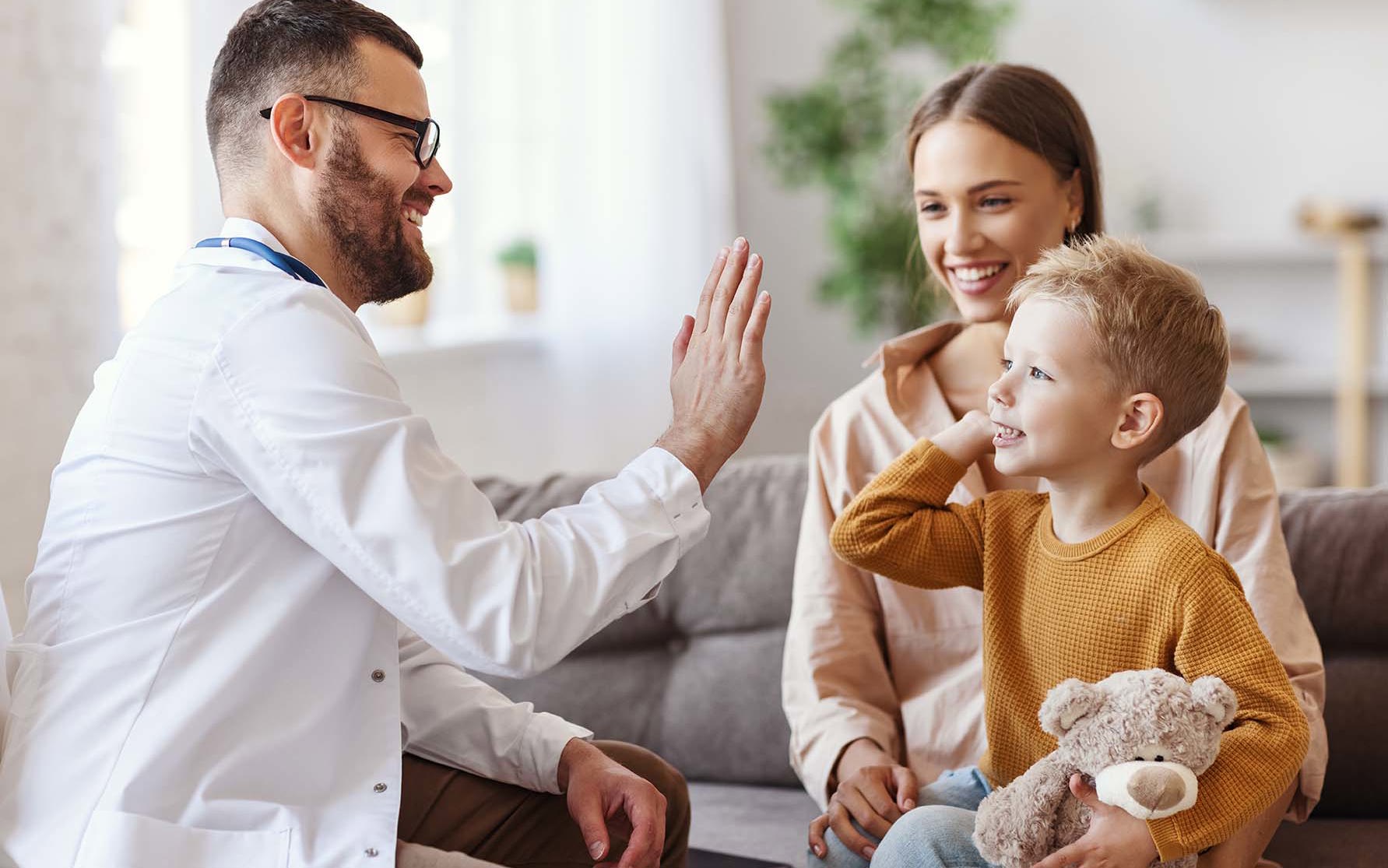 family doctor pediatrician conducts examination of child boy and giving high five to him.